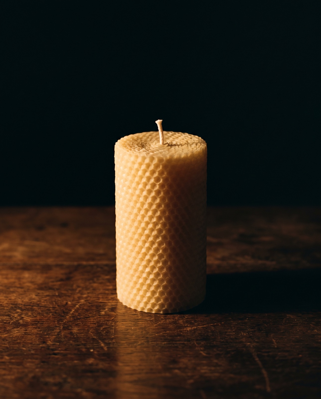 An unlit hand-poured beeswax pillar candle